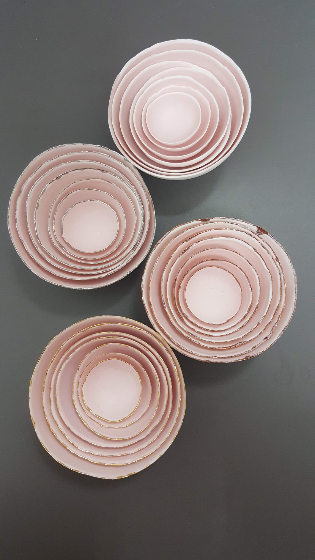 Set of 7 stoneware fine bone china nesting bowls in dusty pink and white with various finishes.