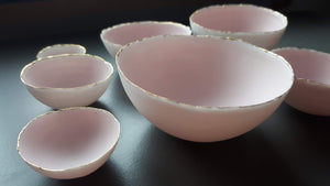 Set of 7 stoneware fine bone china nesting bowls in dusty pink and white with various finishes.