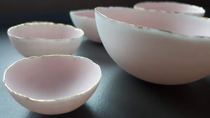 Set of 7 stoneware fine bone china nesting bowls in dusty pink and white with various finishes.