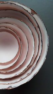 Set of 7 stoneware fine bone china nesting bowls in dusty pink and white with various finishes.