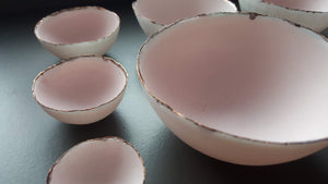 Set of 7 stoneware fine bone china nesting bowls in dusty pink and white with various finishes.