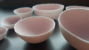 Set of 7 stoneware fine bone china nesting bowls in dusty pink and white with various finishes.