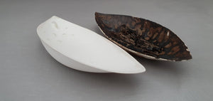 A set of two stoneware fine china vessels with dark glaze and mother of pearl resembles Lilly petals.