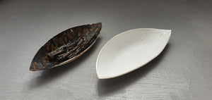 A set of two stoneware fine china vessels with dark glaze and mother of pearl resembles Lilly petals.