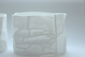 Crumpled paper looking vessel made out of fine bone china with a hint of mother of pearl, iridescent