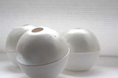 White spheres made from fine bone china with mat ivory mother of pearl on the top half