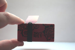 Red gift box matchbox style with black floral pattern and ribbon